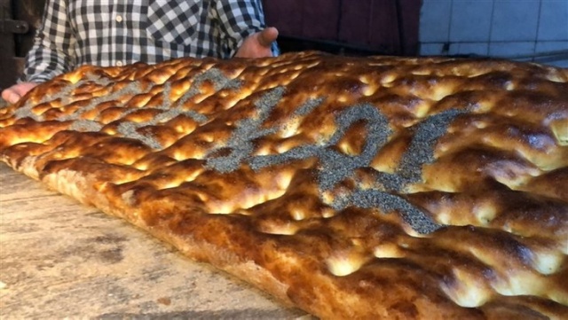 Kilolarca hamurdan yapılan 2 metrelik 'Evde Kal Türkiye' yazılı pide açık artırmayla satıldı.